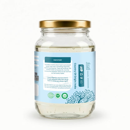 A clear glass jar of coconut oil with a gold metal lid and a light blue label, shown on a clean white background. The label features the brand name 'Safi' and text indicating 'Pure Organic Coconut Oil'