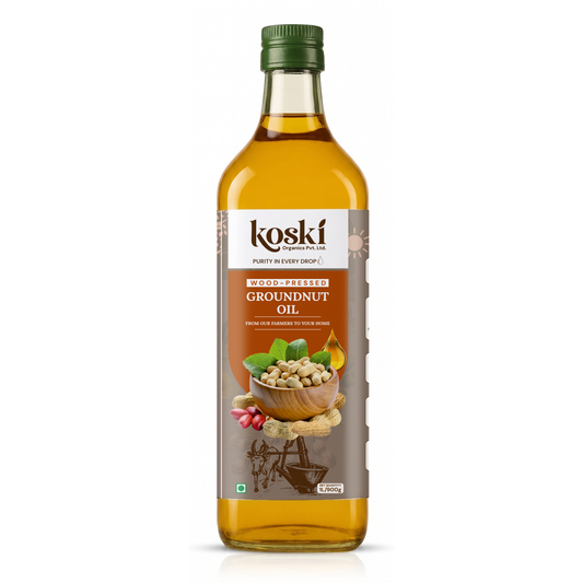 A bottle of Koski Wood Pressed Groundnut Oil with a green cap and a brown and white label showing peanuts and green leaves, set against a plain white background.