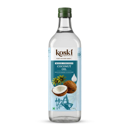 A bottle of Koski WoodPressed Coconut Oil on a clean white background. The clear glass bottle features a green screw cap and a light blue label with illustrations of a coconut, green leaves, and a traditional coconut grinder.
