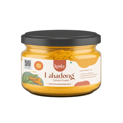 A jar of Koski Organics LaKadong Turmeric Powder on a plain white background. The product is in a clear glass jar showing the bright yellow turmeric powder inside, topped with a black lid