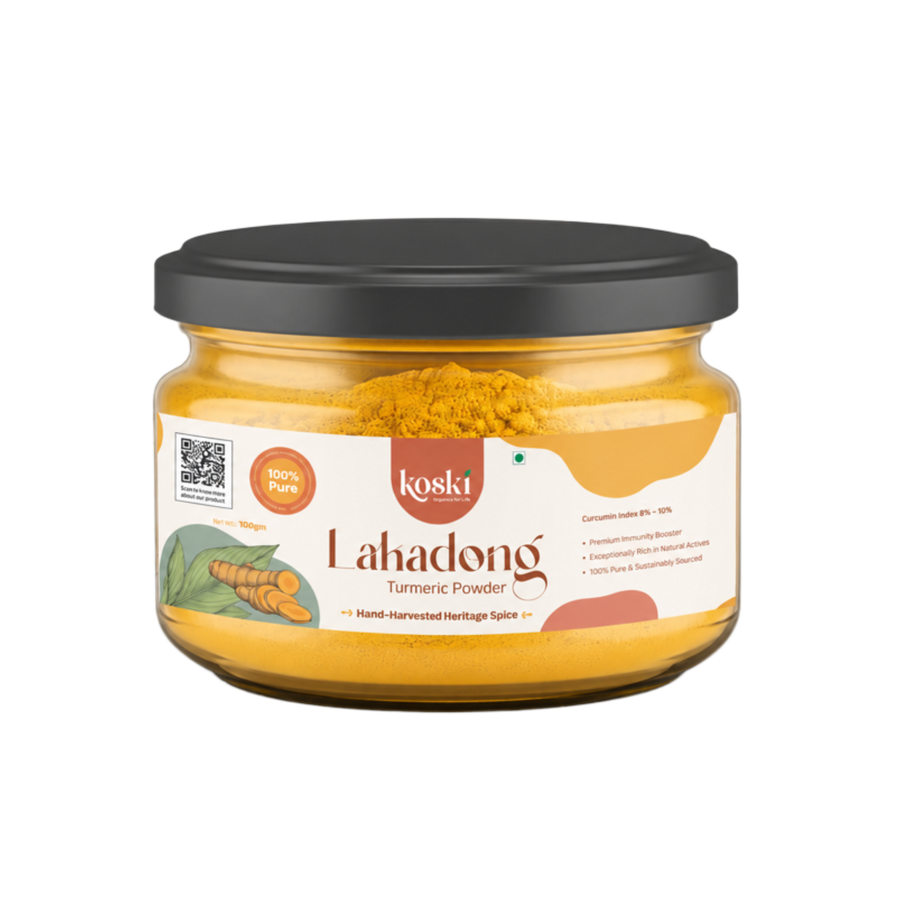 A jar of Koski Organics LaKadong Turmeric Powder on a plain white background. The product is in a clear glass jar showing the bright yellow turmeric powder inside, topped with a black lid