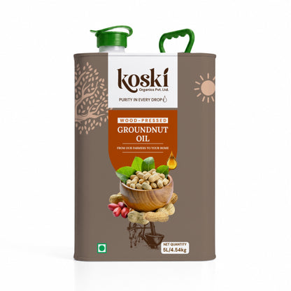 A 5L metal can of Koski Organic Groundnut Oil with a brown body, green plastic cap and handle, and a central label showing peanuts, ginger, and green leaves