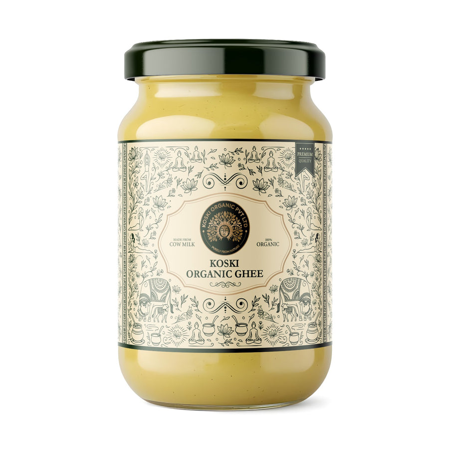 A glass jar of Koski Organics Gir Cow A2 Ghee with a dark green lid and a detailed cream-colored label featuring black illustrations of animals and plants. The ghee inside is a warm yellow color, visible through the clear glass.