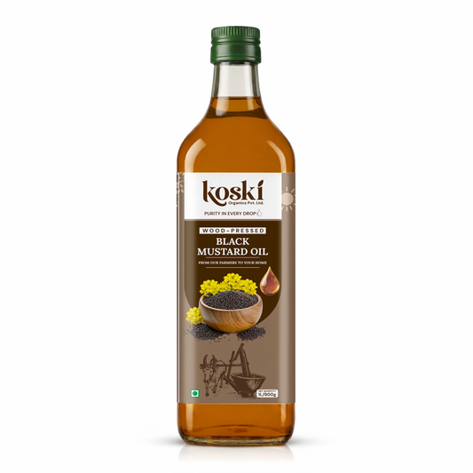 A bottle of Koski Wood-Fired Black Mustard Oil on a clean white background. The bottle is made of clear glass showing the golden-brown oil inside, has a dark green cap, and a brown label with illustrations of mustard seeds and flowers.